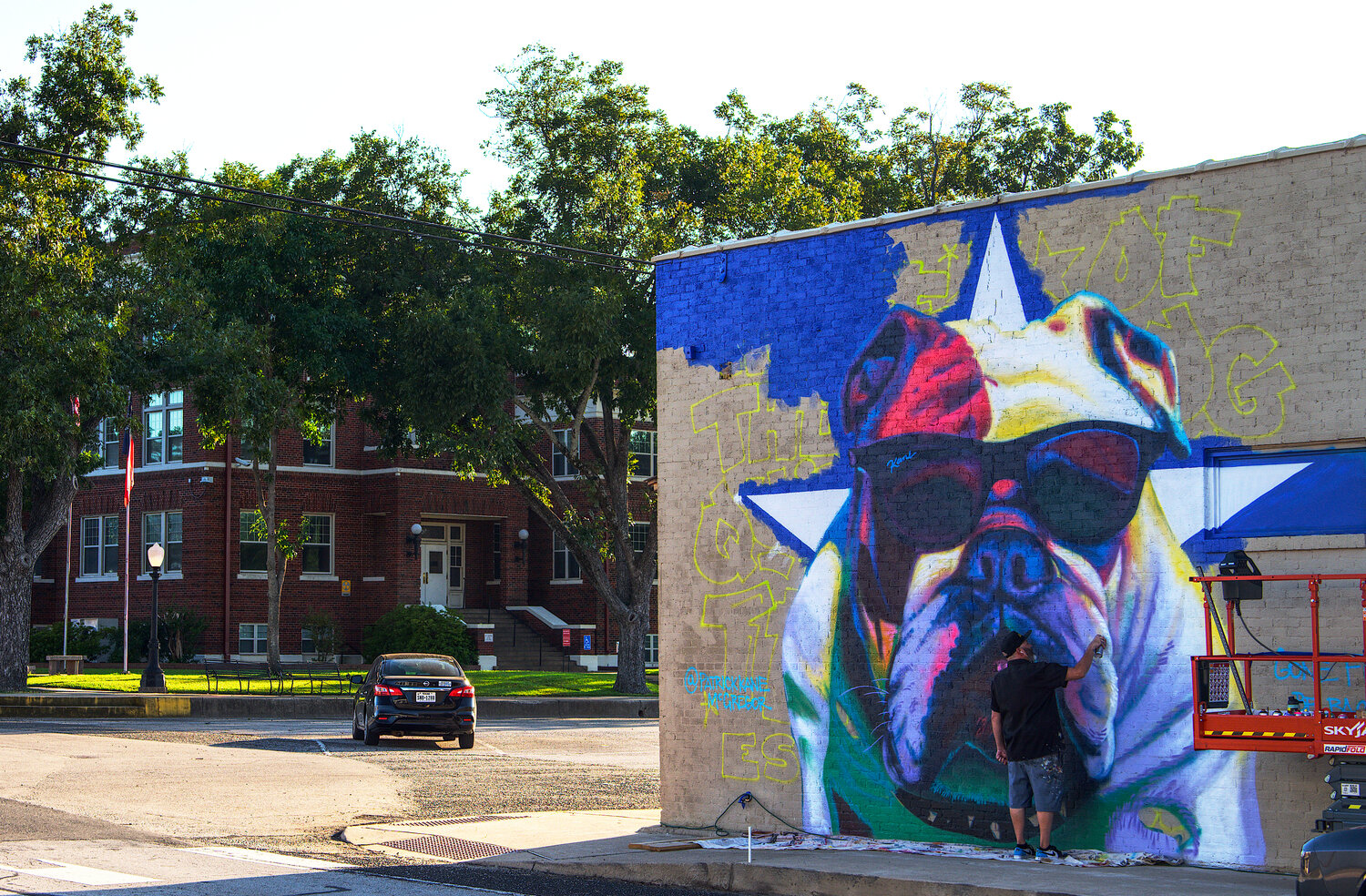 Patrick McGregor makes his bulldog begin to come to life Monday evening on the eastern wall of Dani's Sidekick, across the square from the Wood County Courthouse (background, left). [peruse the progress]